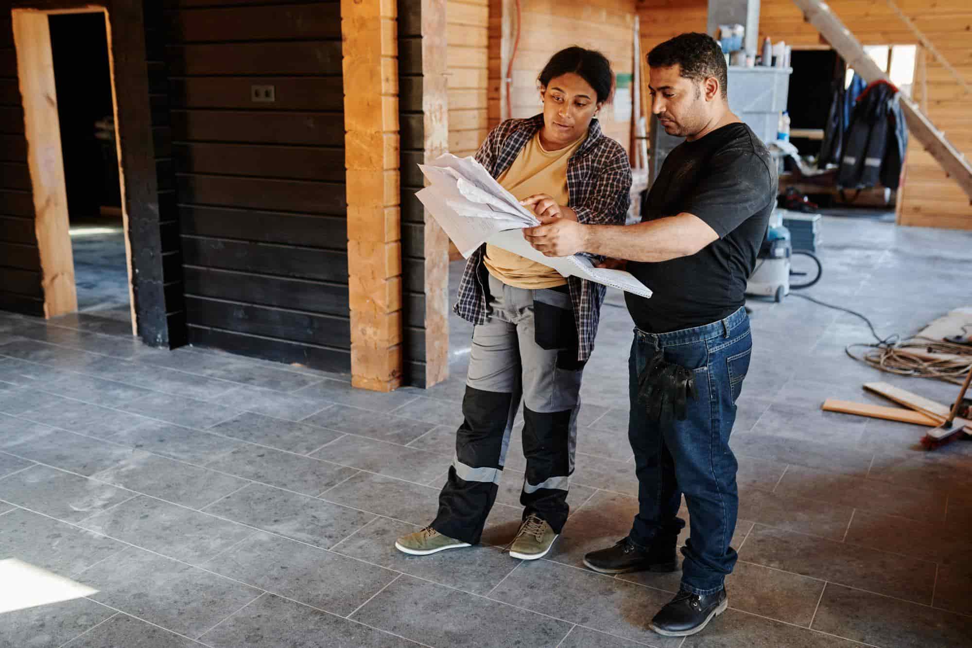 Two contractors going over plans inside a home under construction